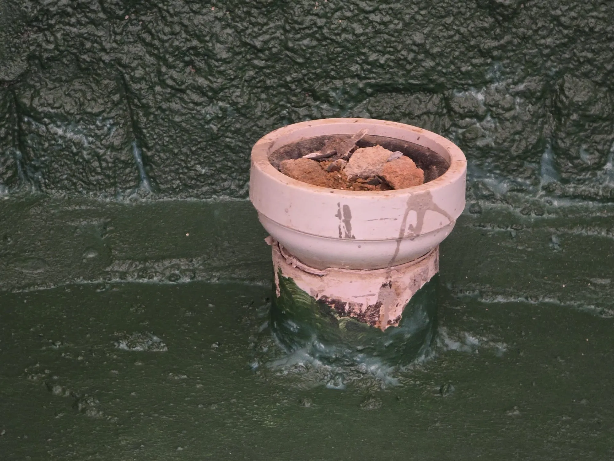 Waterproofing membrane worked around a toilet outlet and up the wall — the detail where most ceiling leaks begin