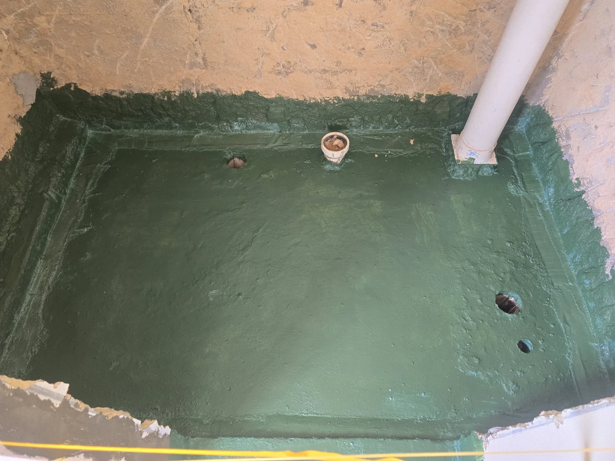 SealForce WB20 trial batch applied across a hacked HDB toilet floor and up the walls, around the soil stack and floor outlet, before the flood test and tiling